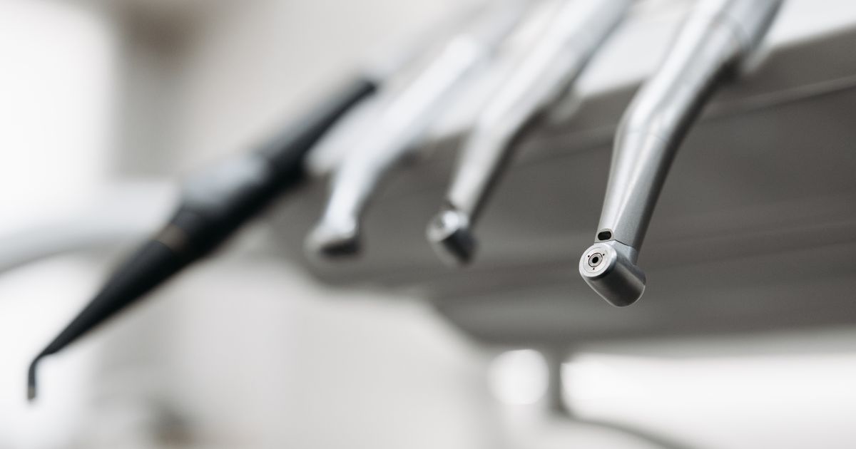 Stainless steel dental handpieces hanging from a dental unit in a bright clinic, illustrating the rules on advertising dental services in Singapore.
