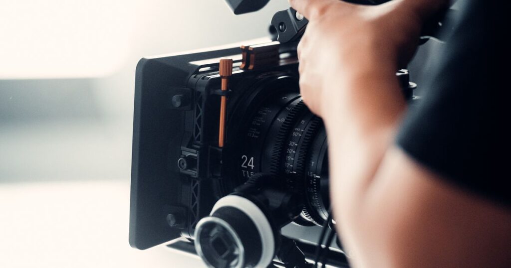A camera operator adjusting a cinema camera on a bright set, illustrating the work pass rules for foreign influencers, models and film crew on Singapore shoots.