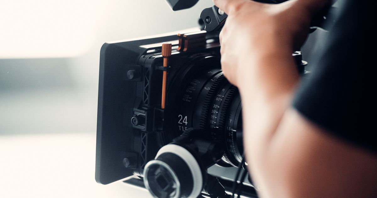 A camera operator adjusting a cinema camera on a bright set, illustrating the work pass rules for foreign influencers, models and film crew on Singapore shoots.