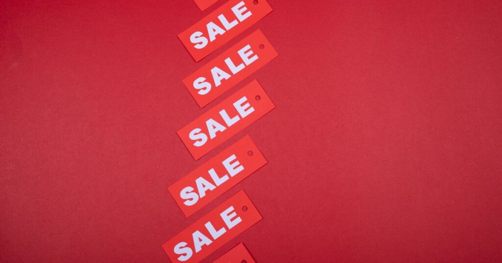 A diagonal row of red SALE price tags on a red background, illustrating the rules on displaying GST-inclusive prices in Singapore advertising.