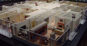 A detailed architectural scale model of a furnished condominium floor with open-plan units, illustrating the advertising and show-unit rules for property developers in Singapore.
