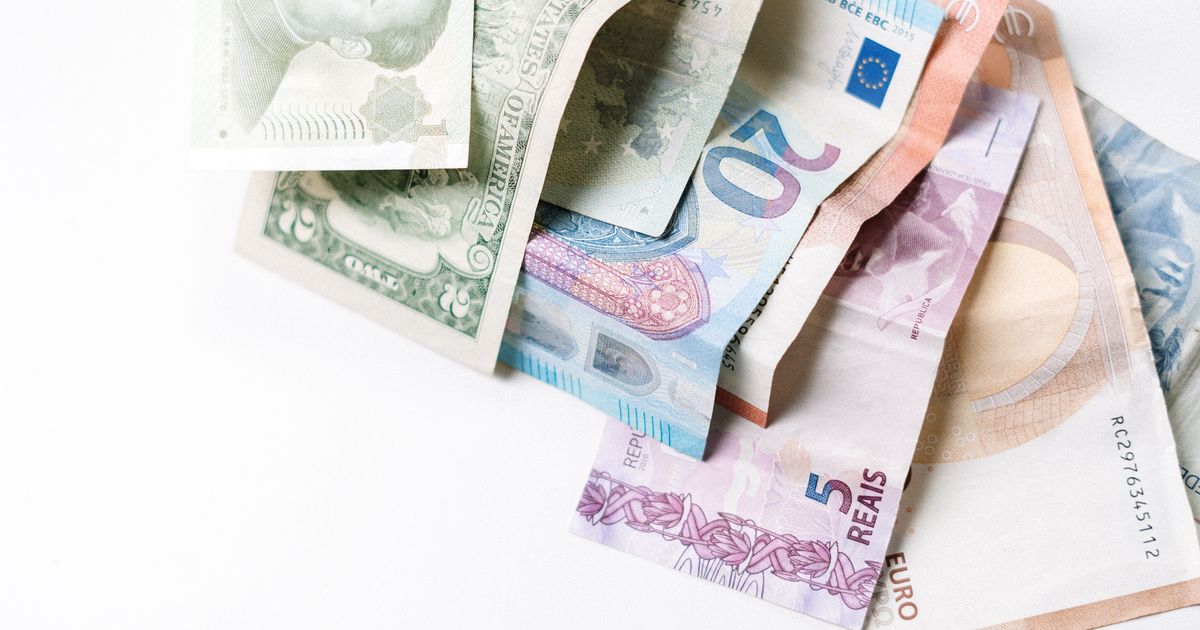 Assorted foreign banknotes, including US dollars, euros and Brazilian reais, fanned out on a white surface, illustrating the rules on advertising remittance and money-changing services in Singapore.
