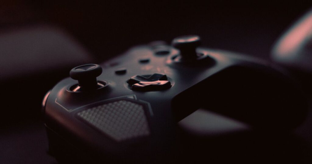Close-up of a dark, unbranded game controller in low light, illustrating the rules on advertising video games in Singapore.